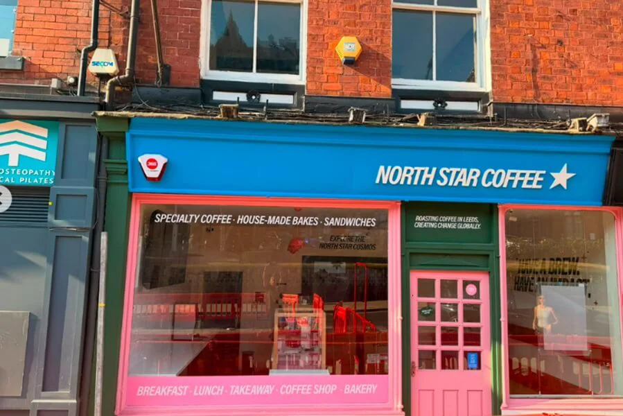 An image of the blue, green, and pink North Star Coffee storefront signage and window graphics.